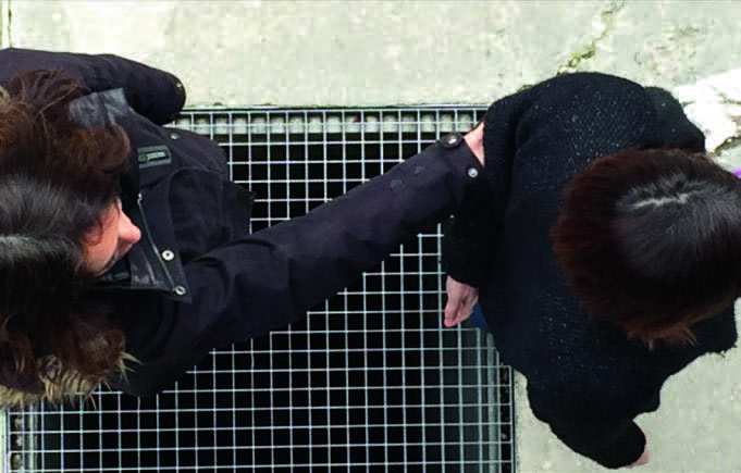 Photo de deux personnes pratiquant la technique de guide. Le guide est en avant d'un pas et son bras et est dans son dos. La personne derrière elle attrape son bras avec son propre bras tendu.