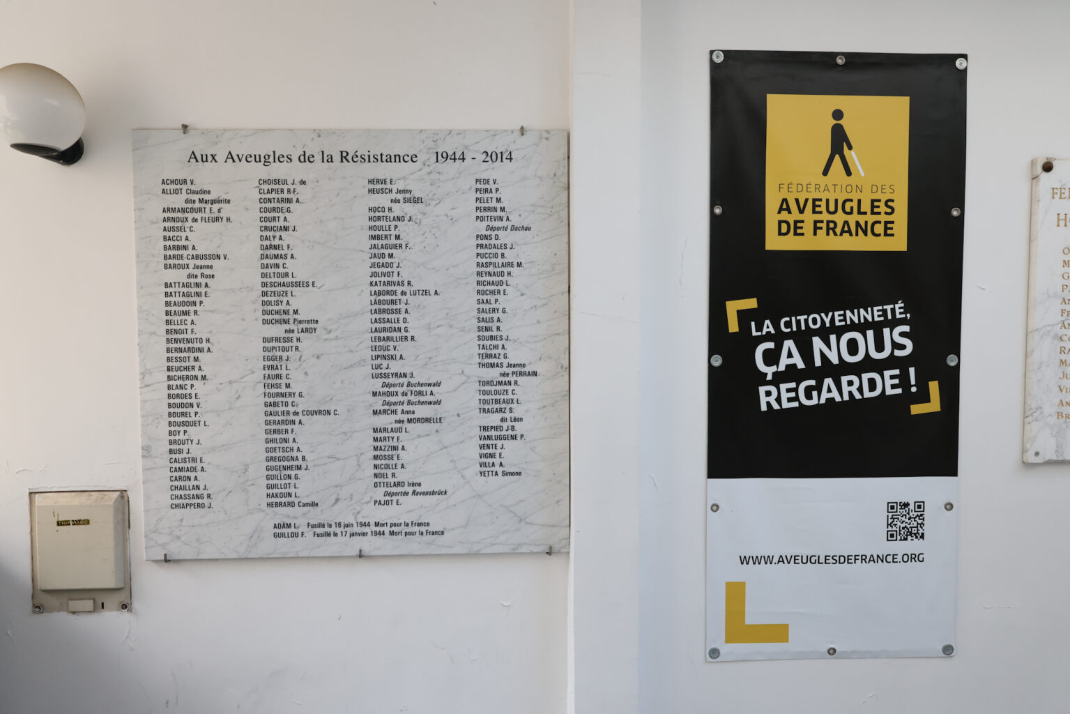 Photo de la plaque commémorative dédiée aux aveugles de la résistance. À côté, un kakemono aux couleurs de la Fédération des Aveugles de France est affiché.